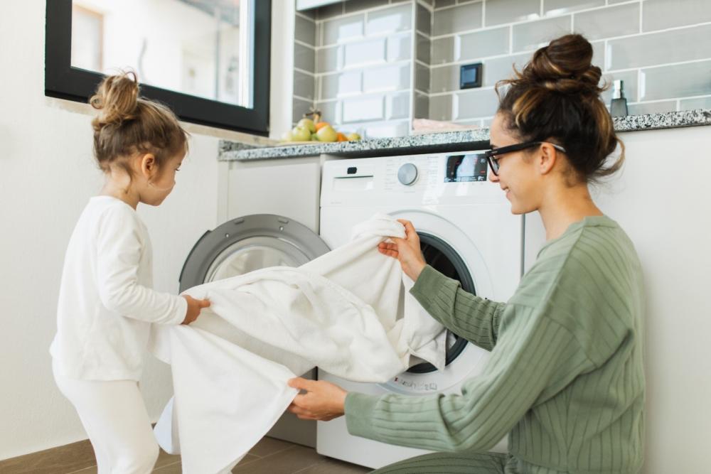 Mother and daughter loading washing machine