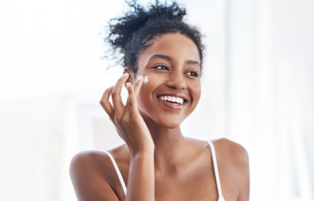 african american woman applying facial moisturizer