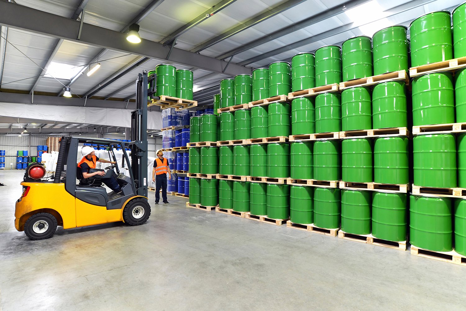 Green barrels filled with sustainable products line the wall of a distribution center