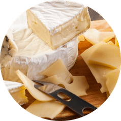 An assortment of dairy products including a wedge of brie and slices of swiss cheese