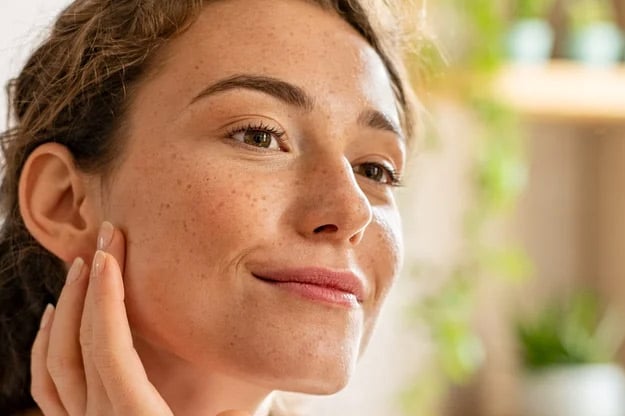 A smiling woman touching her cheek