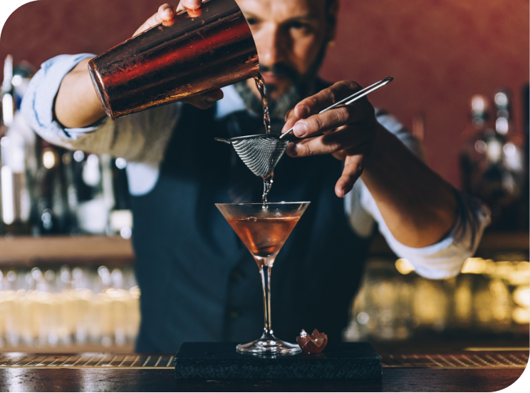 man pouring a crafted martini at a bar