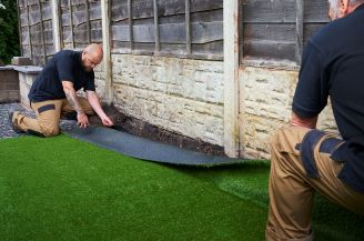 Two men installing synthetic turf with water-based rubber adhesion