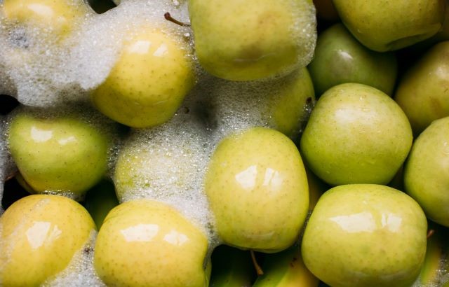 Yellow apples being washed in bulk with foam around them