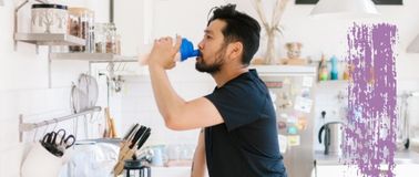 A man stands in his kitchen while enjoying a post-workout smoothie to support active nutrition
