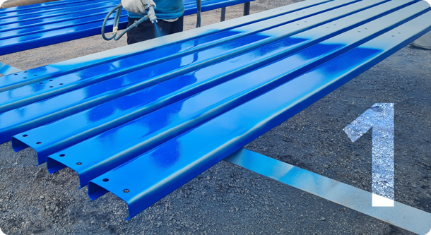 Metal sheeting with a blue coating being applied by an industrial air sprayer