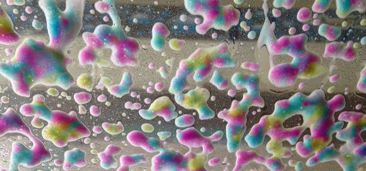 Soapy suds trickle down a windshield while driving through a car wash tunnel