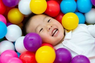 Child playing in colorful plastic ball pit