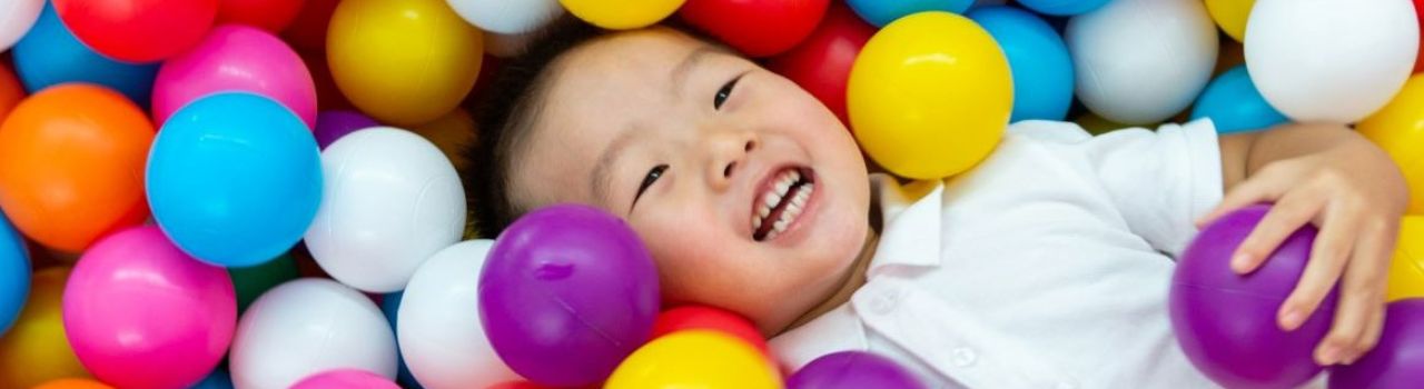 Child playing in colorful plastic ball pit