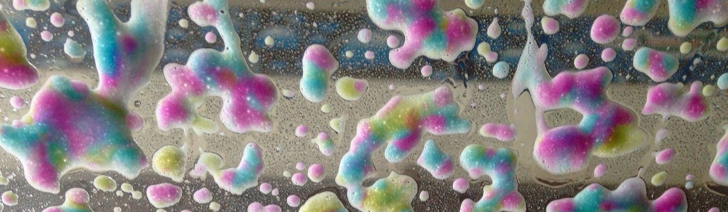 Colorful foam soap seen from the inside of a car windshield in a carwash