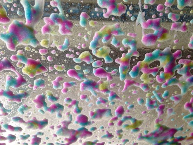 Colorful foam soap seen from the inside of a car windshield in a carwash