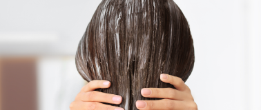 A woman applies conditioner to her long hair