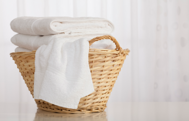 white folded towels set inside of a rattan basket