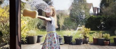  Young girl cleaning a glass patio window