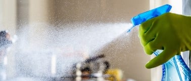 Blue spray bottle with hard surface cleaner being sprayed