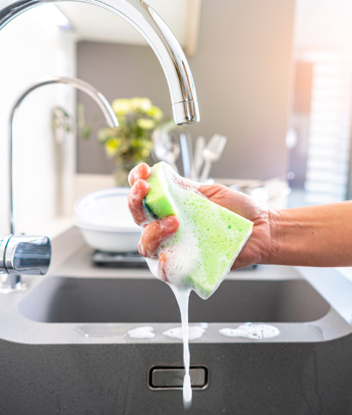 soapy sponge being rung out over the kitchen sink