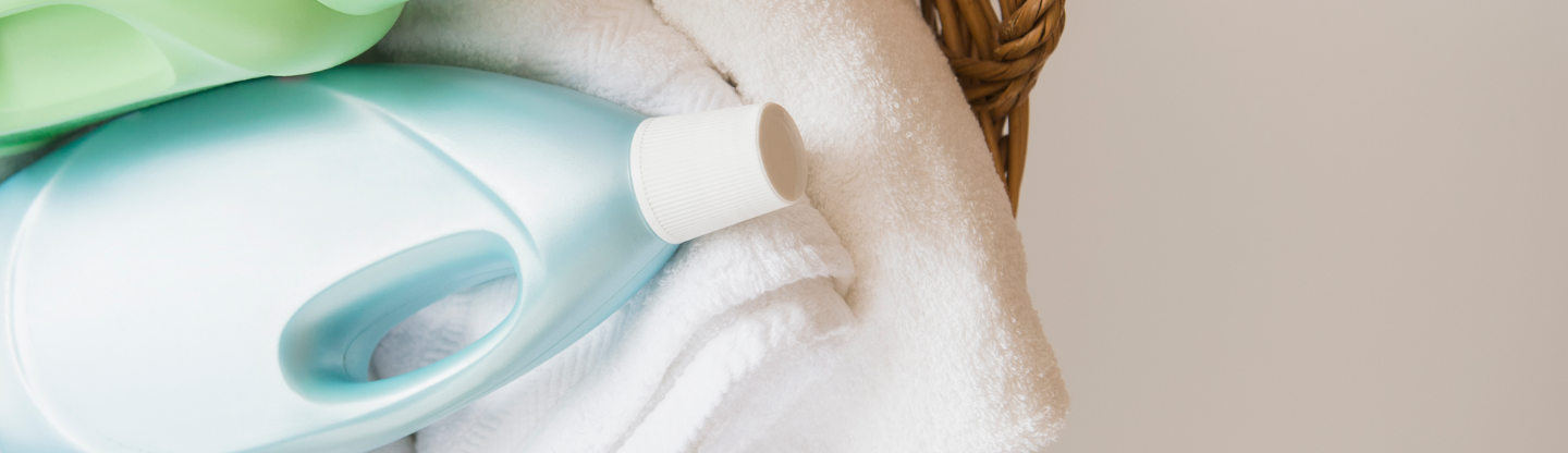 launry softner bottle laying ontop of a towel in a basket