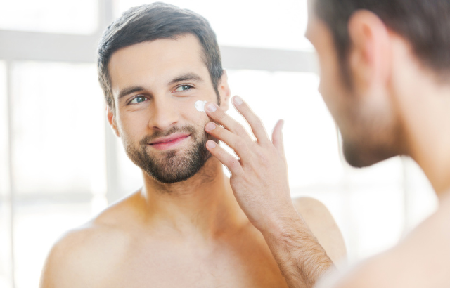 man putting moisturizer on his cheek
