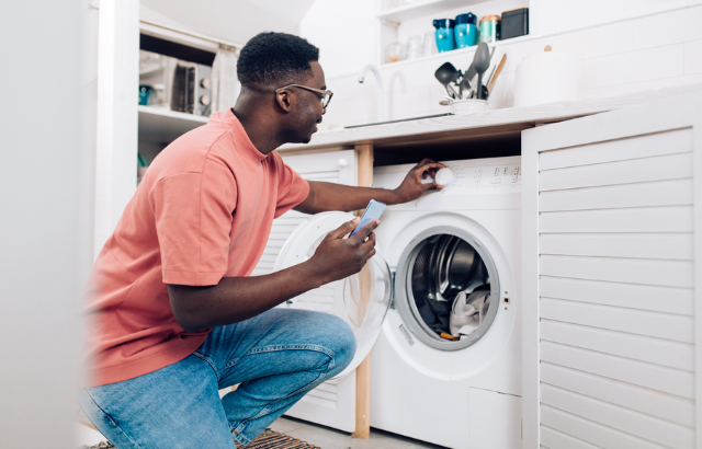 man adjusting the washing machine dial to start a load of laundry