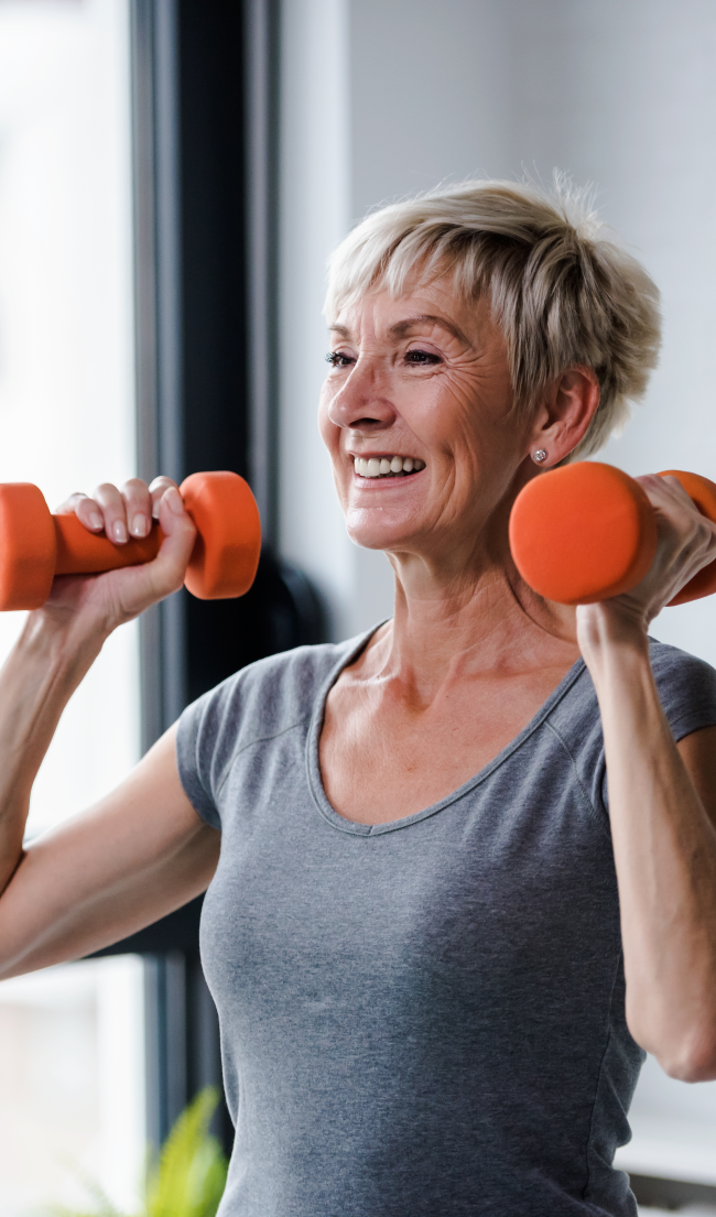 An older woman lifting small dumbbells in a wellness facility.