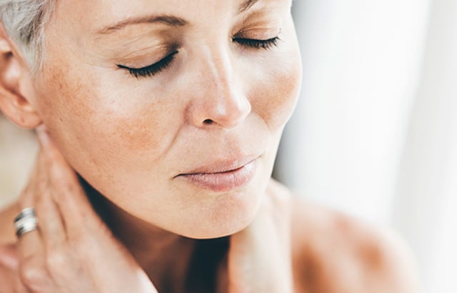 older woman holding her neck with her eyes shut