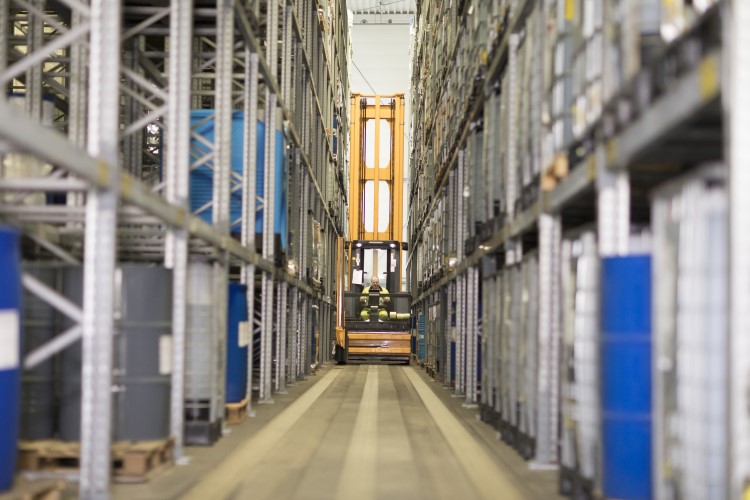 A forklift drives between aisles of a plastic additives distribution center