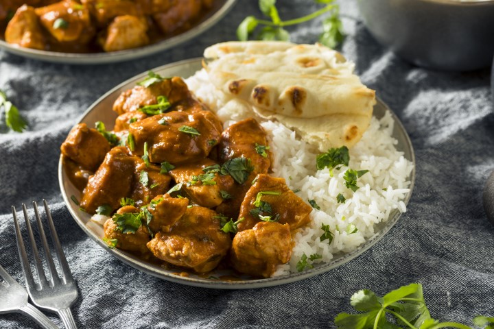 Healthier dish of plant protein with rice and naan sits on a table top with eating utensils