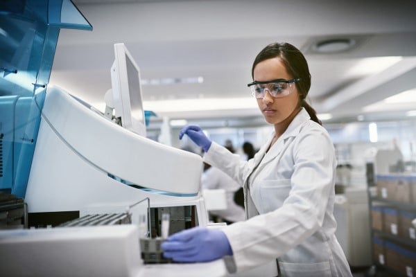 scientist wearing a lab coat and safety glasses in a pharmaceutical lab