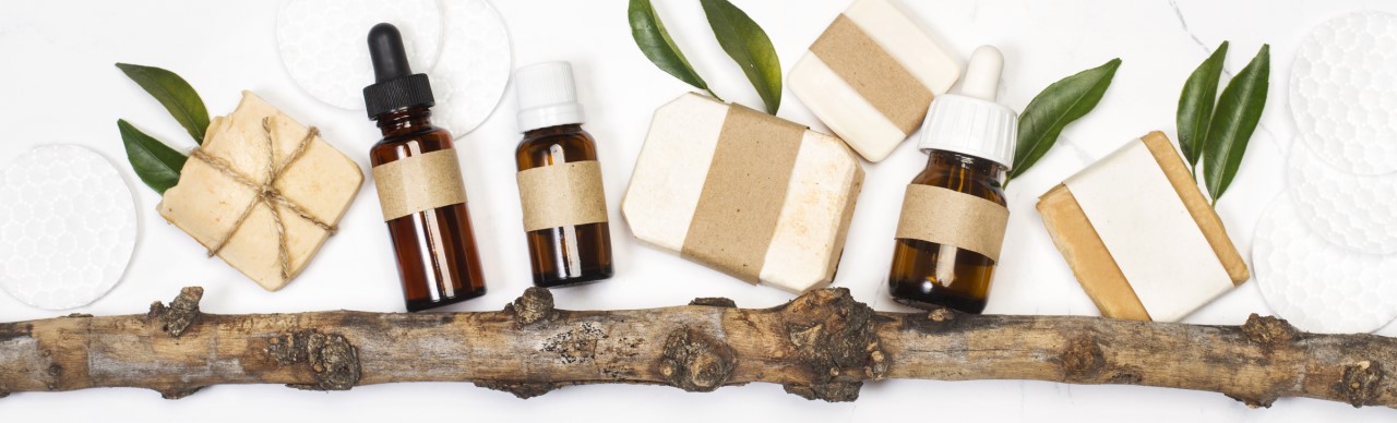 Natural beauty and personal care products are displayed with a branch and leaves