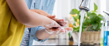 Close up of parent and child washing hands at a kitchen sink