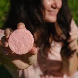 Woman holding up a round bar of soap